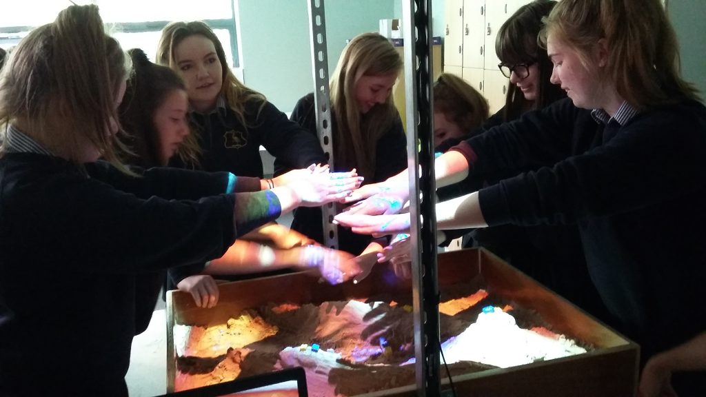 Students engaging with the sandbox to learn about flooding