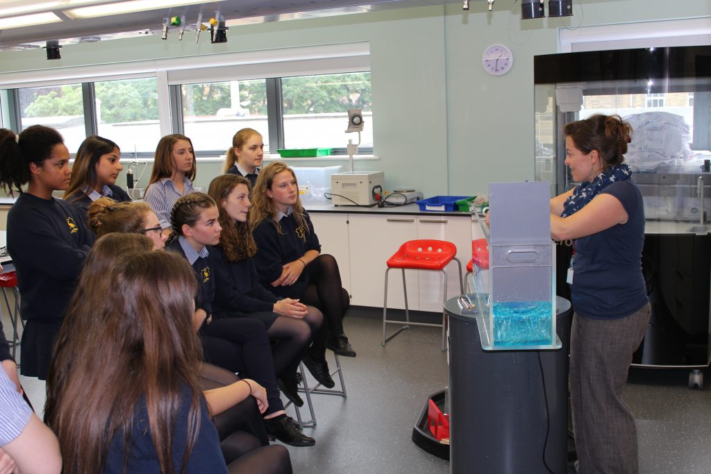 Alex Scott uses the mini-flume to explain the causes of flooding to students at SGHS